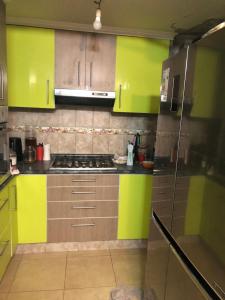 圣地亚哥Tu espacio Re - Cuarto descanso的厨房配有绿色和黄色的橱柜和炉灶。