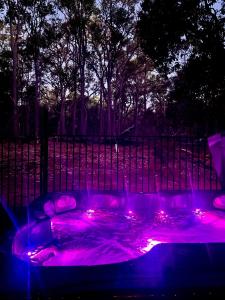 楠立Jarrah Glen Cabins的围栏前的紫色灯热水浴池
