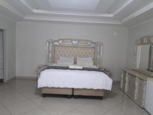 曼齐尼Rest Camp Lodge的一间白色客房内配有一张大床的卧室