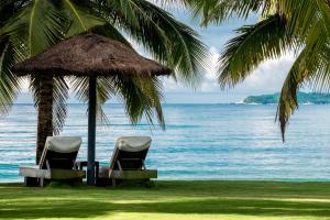 三亚三亚安隅酒店的海滩上一把稻草伞下的两把椅子