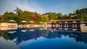 美奈维多利亚潘切海滩Spa度假酒店的一个带遮阳伞、椅子和树木的大型游泳池