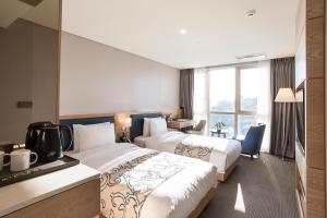 釜山Centum Prime Hotel的酒店客房配有两张床和一张书桌