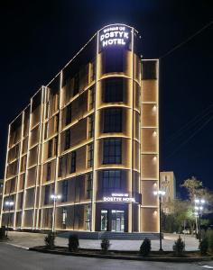 阿克套Dostyk Business Hotel的一座建筑物,上面有夜间标志