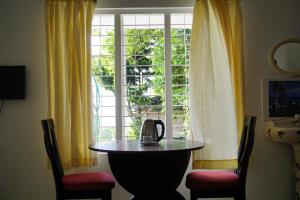 钦纳卡纳Classiyo Green Mount Resort的窗户前的桌子和茶壶