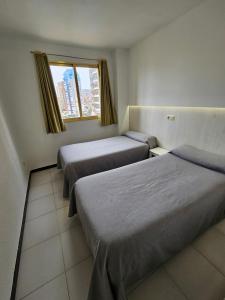 贝尼多姆玛丽亚维多利亚公寓的带三张床和窗户的客房