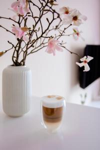 波兹南Apartament Bimba - Free Parking的白色花瓶,花朵和咖啡