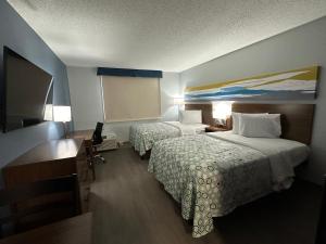 科特兰HomeTowne Studios by Red Roof & Conference Center Cortland的酒店客房配有两张床和一张书桌