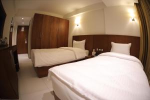 卡尔巴拉Coral Hotel Karbala的酒店客房,配有两张带白色床单的床