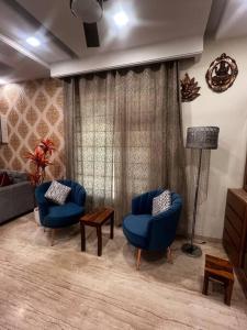 钱德加尔Kamz Homestay Chandigarh 35的客厅配有2把蓝色椅子和1盏灯