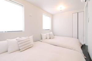 广岛bHOTEL Komachi - Apt for 6ppl few mins walk to Peace Park的白色客房的两张床,设有两扇窗户