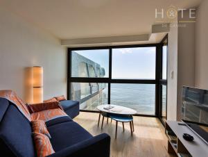 莱萨布勒-多洛讷Appartement au pied de la plage, vue imprenable sur la mer的客厅设有蓝色的沙发和大窗户