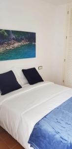 皮内达德马尔Tropic Maresme的卧室配有一张白色大床,墙上挂有绘画作品