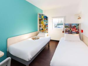 Saint-CergueshotelF1 Annemasse Hotel Renove的蓝色墙壁客房的两张床