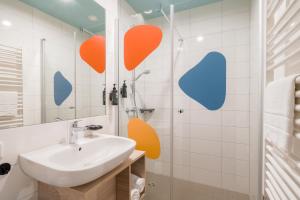 慕尼黑Ramada Encore by Wyndham Munich Messe的墙上设有带水槽和橙色心的浴室