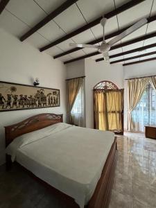 尼甘布Village Inn Resort的一间卧室配有一张大床和吊扇