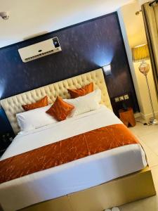 雅温得Boun's Hotel的一间卧室配有一张带橙色和白色枕头的大床