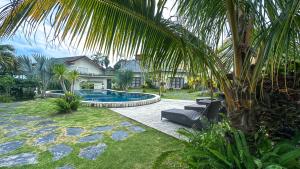 SidomuktiArtha Cottages的一座带游泳池和棕榈树的房子