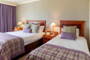 特里姆奈克斯布鲁科高尔夫度假酒店的酒店客房配有两张带紫色枕头的床