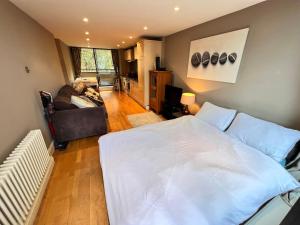 伦敦Happy River Thames View Entire Apartment的卧室配有一张白色的大床和一张沙发。