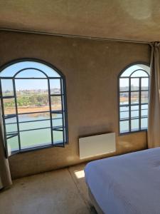 艾宰穆尔L'Oum Errebia的两扇窗户,房间带一张床和水