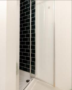 伦敦Primrose Hill Charming 1-Bed Flat的玻璃门和黑色瓷砖墙淋浴