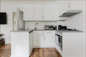 伦敦Primrose Hill Charming 1-Bed Flat的白色的厨房,配有白色橱柜和不锈钢用具