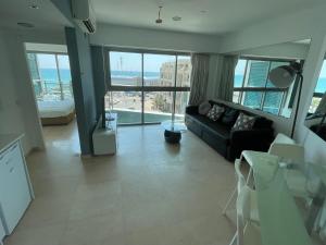 荷兹利亚Bמלון דירות אוקיינוס במרינה דירות עם נוף לים的客厅设有黑色沙发和大窗户