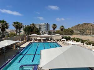 荷兹利亚Bמלון דירות אוקיינוס במרינה דירות עם נוף לים的一个带白色遮阳伞的游泳池和一个度假村