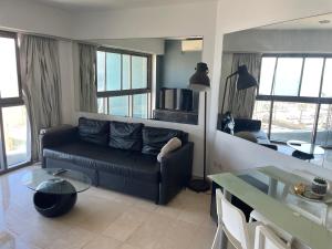 荷兹利亚Bמלון דירות אוקיינוס במרינה דירות עם נוף לים的客厅配有黑色沙发和桌子