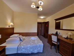 什切青博纳卡扎酒店的酒店客房带一张床、一张书桌和一面镜子