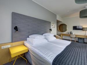 派尔努爱沙尼亚度假酒店及Spa的卧室配有一张白色大床和黄色凳子