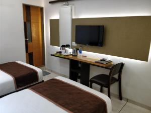 瓦皮Hotel Royal Shelter Vapi的酒店客房设有两张床和一张书桌及电视