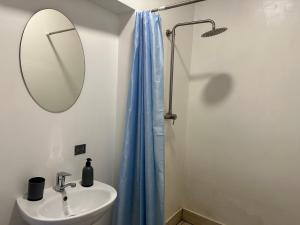 罗夫诺Апартаменти на вул. Біла,5а的浴室设有水槽和带蓝色淋浴帘的淋浴