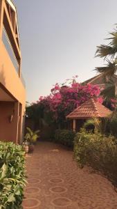 RufisqueRésidence Keur Fleurie Sénégal的砖砌的走道,旁边是一座粉红色花卉的建筑