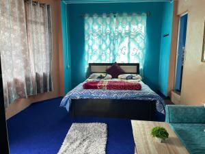 MirikPradhan Homestay Mirik - Homestay beside Mirik Lake的一间卧室配有一张蓝色墙壁的床和一扇窗户