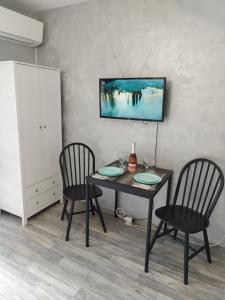 瓦尔纳Aпартамент 5的餐桌、两把椅子和墙上的电视