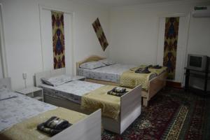 布哈拉Orzu Guest House的一间设有三张床和电视的房间