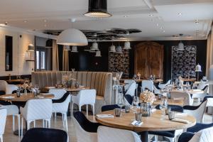 萨莱Le Bailliage Hôtel & Spa的配有木桌和白色椅子的餐厅