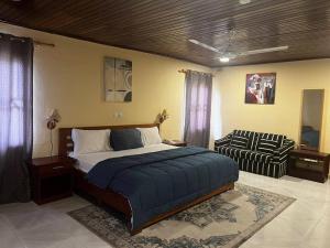 AkropongAmoaba's Inn的一间卧室配有一张大床和一把椅子