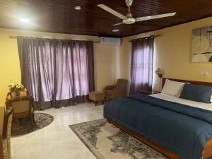 AkropongAmoaba's Inn的一间卧室配有一张床、一把椅子和窗户。