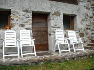 拉比Baita Misseroni Quadrilocale的坐在大楼外的四把白色椅子