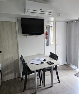 纳博讷普拉日Mobil Home (Clim, TV)- Camping Falaise Narbonne-Plage 4* - 003的餐桌、椅子和墙上的电视