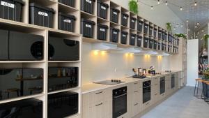 黄金海岸Capsuleaccom Hostel的一间大厨房,配有白色橱柜和黑色家电