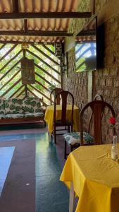 瓜皮米林Suíte serra dos órgãos guapimirim的一间房间,设有两张桌子和一张黄色桌布