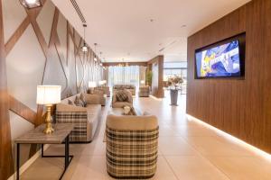 泰布克Enala Hotel - Tabuk的带沙发的客厅和墙上的电视