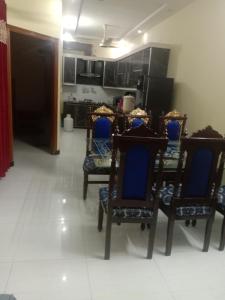 GujrātGujrat Guest House的一间带蓝色椅子的用餐室和一间厨房