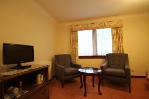 因弗鲁里Strathburn Hotel Inverurie by Compass Hospitality的客厅配有两把椅子和电视