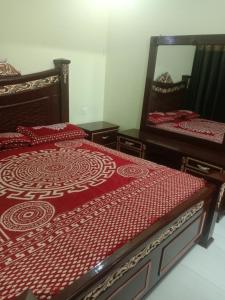 GujrātGujrat Guest House的一间卧室配有两张床和镜子