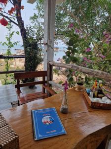 富国Butterfly Rose Beach Resort Phú Quốc Francophone的一张木桌,上面有一本书