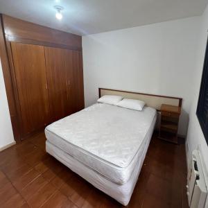 瓜鲁雅APARTFLAT Pitangueiras a 3 minutos da praia!的卧室配有白色的床和木制橱柜。